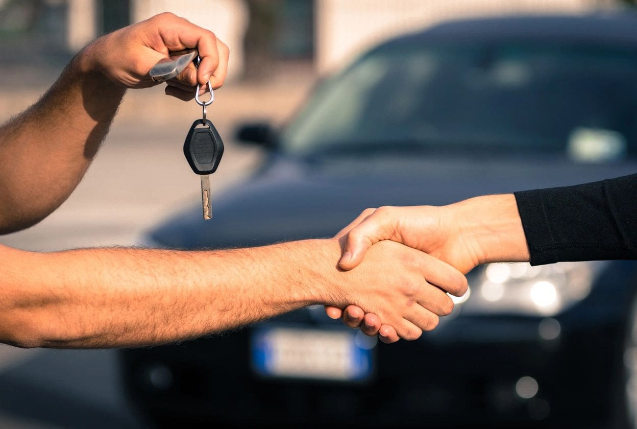 A man shaking hands with another person holding keys.